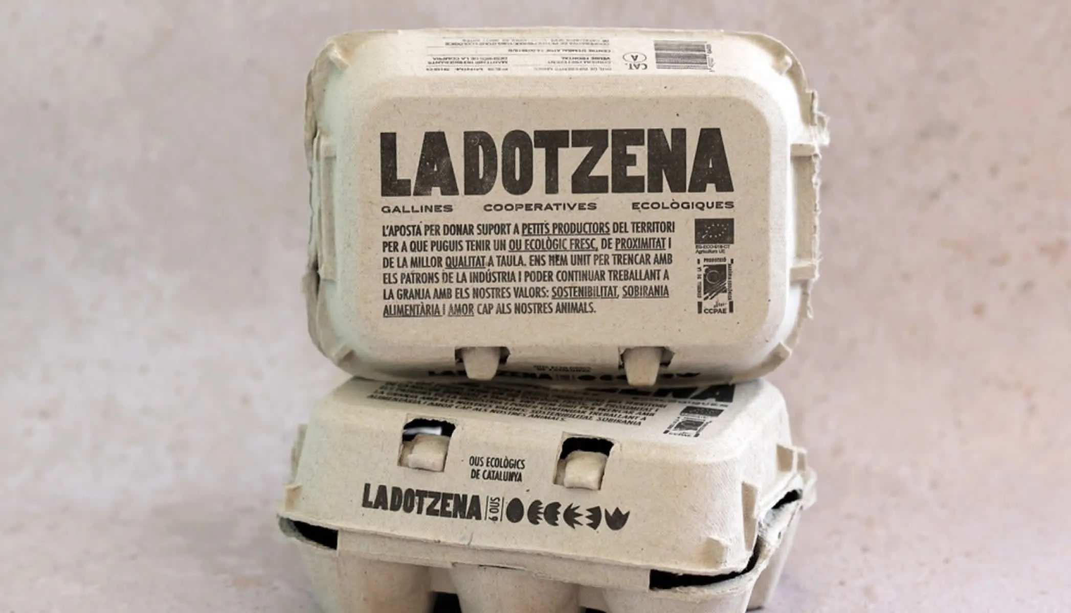 Dos cajas de huevos de La Dotzena apiladas, con el nombre de la cooperativa y su lema impresos en el cartón