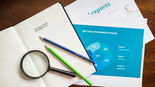 Person reviewing documents and screens with industrial process charts in a planning meeting