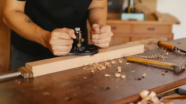 Artesano trabajando una pieza de madera a medida sobre un banco de taller