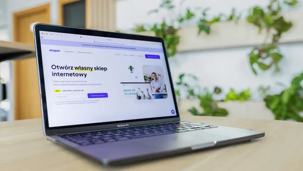 Portàtil obert mostrant una web de comerç electrònic en un escriptori d'oficina moderna
