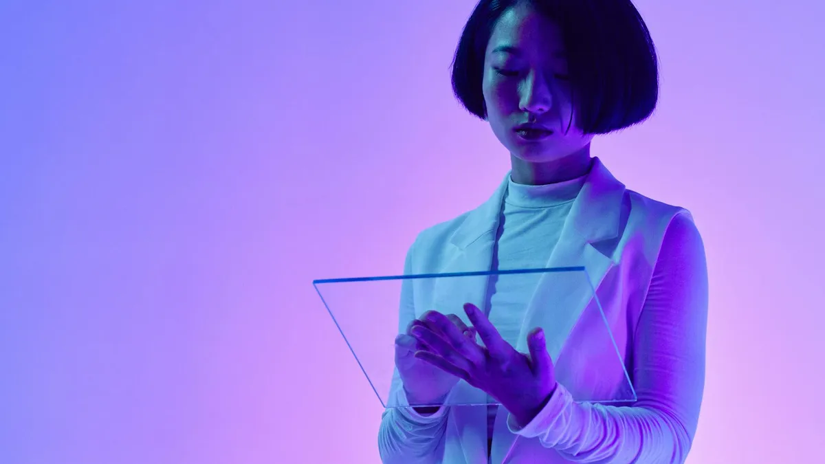 Person interacting with a transparent digital screen in a modern workspace with vibrant studio lighting